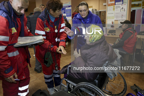 Paramedics talk to an elderly woman in a wheelchair at an evacuation point during the arrival of people from the Kupiansk community in Khark...