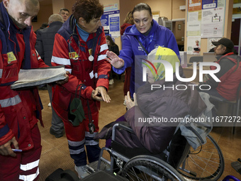 Paramedics talk to an elderly woman in a wheelchair at an evacuation point during the arrival of people from the Kupiansk community in Khark...