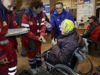 Paramedics talk to an elderly woman in a wheelchair at an evacuation point during the arrival of people from the Kupiansk community in Khark...