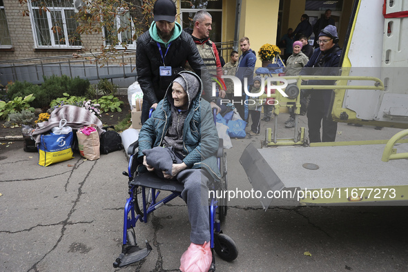 A man pushes an elderly woman in a wheelchair at an evacuation point during the arrival of people from the Kupiansk community in Kharkiv, Uk...