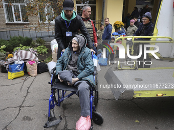 A man pushes an elderly woman in a wheelchair at an evacuation point during the arrival of people from the Kupiansk community in Kharkiv, Uk...