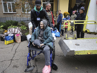 A man pushes an elderly woman in a wheelchair at an evacuation point during the arrival of people from the Kupiansk community in Kharkiv, Uk...