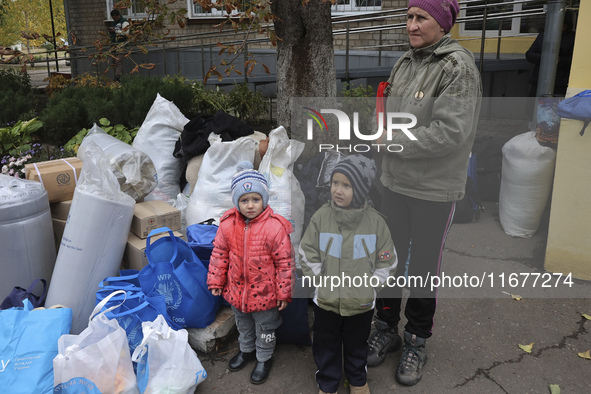 A little boy and girl stand by a woman as people from the Kupiansk community arrive at an evacuation point in Kharkiv, Ukraine, on October 1...