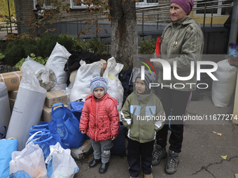 A little boy and girl stand by a woman as people from the Kupiansk community arrive at an evacuation point in Kharkiv, Ukraine, on October 1...