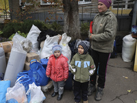 A little boy and girl stand by a woman as people from the Kupiansk community arrive at an evacuation point in Kharkiv, Ukraine, on October 1...