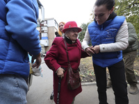 A volunteer supports an elderly woman at an evacuation point during the arrival of people from the Kupiansk community in Kharkiv, Ukraine, o...