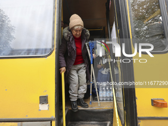 An elderly woman with crutches gets out of a bus at an evacuation point during the arrival of people from the Kupiansk community in Kharkiv,...