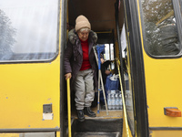 An elderly woman with crutches gets out of a bus at an evacuation point during the arrival of people from the Kupiansk community in Kharkiv,...