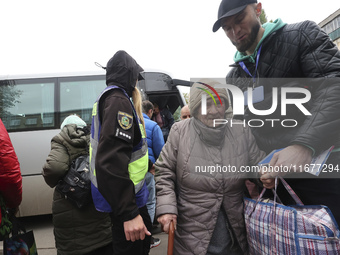 A volunteer supports an elderly woman at an evacuation point during the arrival of people from the Kupiansk community in Kharkiv, Ukraine, o...