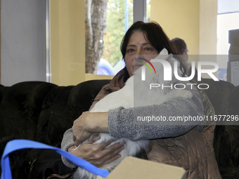 A woman holds a white cat at an evacuation point during the arrival of people from the Kupiansk community in Kharkiv, Ukraine, on October 17...