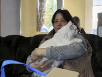 A woman holds a white cat at an evacuation point during the arrival of people from the Kupiansk community in Kharkiv, Ukraine, on October 17...