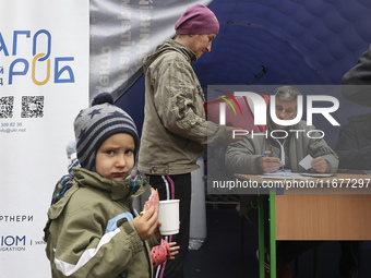 A little boy eats a sandwich as a woman receives help at an evacuation point during the arrival of people from the Kupiansk community in Kha...