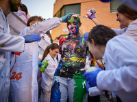 A first-year student from the Faculty of Medicine walks down a hall while seniors paint her with different color paints and glitter as part...