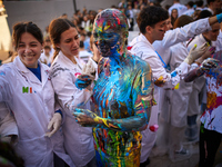 A first-year student from the Faculty of Medicine walks down a hall while seniors paint her with different color paints and glitter as part...