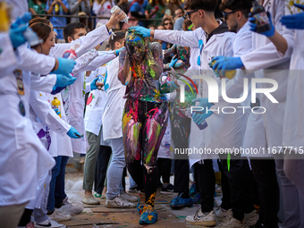 A first-year student from the Faculty of Medicine walks down a hall while seniors paint her with different color paints and glitter as part...