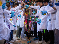 A first-year student from the Faculty of Medicine walks down a hall while seniors paint her with different color paints and glitter as part...