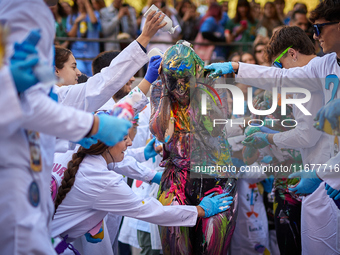 A first-year student from the Faculty of Medicine walks down a hall while seniors paint her with different color paints and glitter as part...