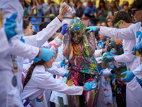 A first-year student from the Faculty of Medicine walks down a hall while seniors paint her with different color paints and glitter as part...