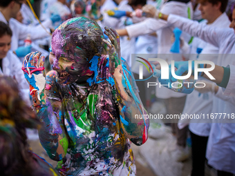 A first-year student from the Faculty of Medicine walks down a hall while seniors paint her with different color paints and glitter as part...