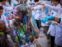 A first-year student from the Faculty of Medicine walks down a hall while seniors paint her with different color paints and glitter as part...