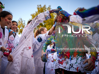 A first-year student from the Faculty of Medicine walks down a hall while seniors paint him with different colors and glitter as part of an...