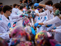 A first-year student from the Faculty of Medicine walks down a hall while seniors paint her with different color paints and glitter as part...