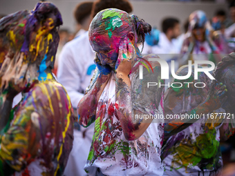 First-year students from the Faculty of Medicine walk down a hall while seniors paint them with different color paints and glitter as part o...