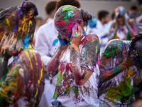 First-year students from the Faculty of Medicine walk down a hall while seniors paint them with different color paints and glitter as part o...