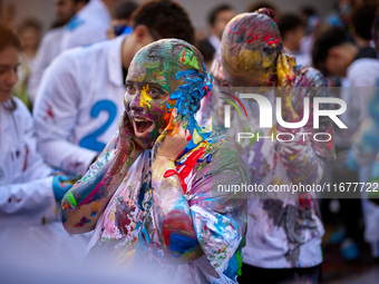 A first-year student from the Faculty of Medicine walks down a hall while seniors paint her with different color paints and glitter as part...