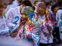 A first-year student from the Faculty of Medicine walks down a hall while seniors paint her with different color paints and glitter as part...