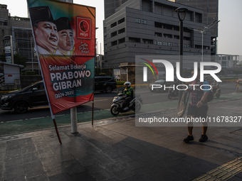 Vehicles pass by a banner that thanks President Joko Widodo and congratulates Indonesia's president-elect Prabowo Subianto and vice presiden...