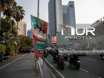 Vehicles pass by a banner that thanks President Joko Widodo and congratulates Indonesia's president-elect Prabowo Subianto and vice presiden...