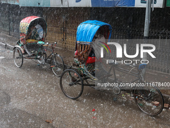 Rickshaw pullers sit under the hood to save themselves from the rain in Dhaka, Bangladesh, on October 18, 2024. (