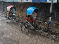 Rickshaw pullers sit under the hood to save themselves from the rain in Dhaka, Bangladesh, on October 18, 2024. (