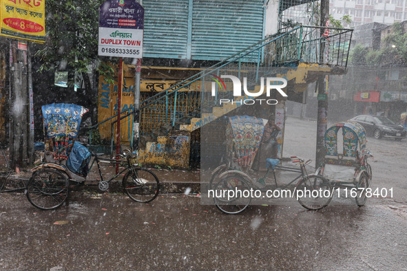 Rickshaw pullers sit under the hood to save themselves from the rain in Dhaka, Bangladesh, on October 18, 2024. 