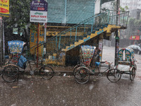 Rickshaw pullers sit under the hood to save themselves from the rain in Dhaka, Bangladesh, on October 18, 2024. (