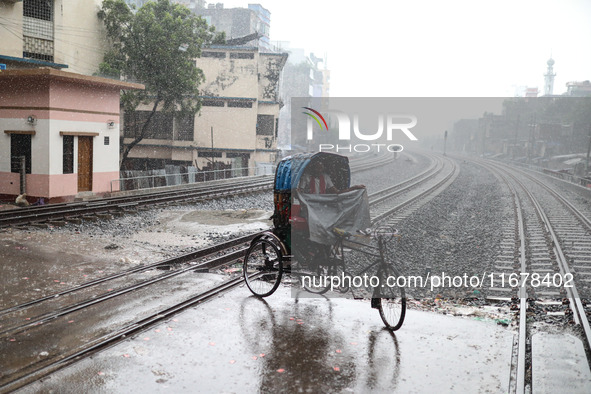 Rickshaw pullers sit under the hood to save themselves from the rain in Dhaka, Bangladesh, on October 18, 2024. 