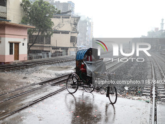 Rickshaw pullers sit under the hood to save themselves from the rain in Dhaka, Bangladesh, on October 18, 2024. (