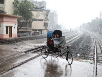 Rickshaw pullers sit under the hood to save themselves from the rain in Dhaka, Bangladesh, on October 18, 2024. (