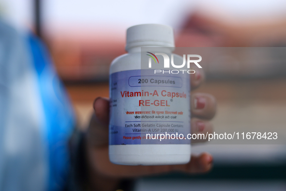 A Nepali health worker displays a bottle containing a Vitamin A capsule in Kathmandu, Nepal, on October 18, 2024. 