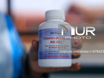 A Nepali health worker displays a bottle containing a Vitamin A capsule in Kathmandu, Nepal, on October 18, 2024. (