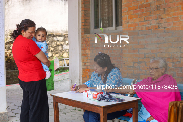 A Nepali health worker (C) records details of a child (L) before administering a ''Vitamin A'' capsule at an inoculation center in Kathmandu...