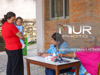 A Nepali health worker (C) records details of a child (L) before administering a ''Vitamin A'' capsule at an inoculation center in Kathmandu...