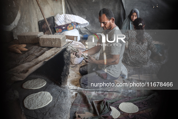 A Palestinian woman bakes bread at a makeshift camp for the internally displaced in Deir al-Balah in the central Gaza Strip on October 18, 2...