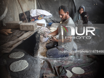 A Palestinian woman bakes bread at a makeshift camp for the internally displaced in Deir al-Balah in the central Gaza Strip on October 18, 2...