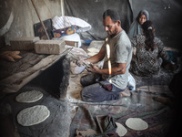 A Palestinian woman bakes bread at a makeshift camp for the internally displaced in Deir al-Balah in the central Gaza Strip on October 18, 2...