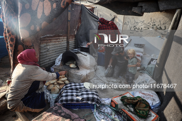 A Palestinian woman bakes bread at a makeshift camp for the internally displaced in Deir al-Balah in the central Gaza Strip on October 18, 2...