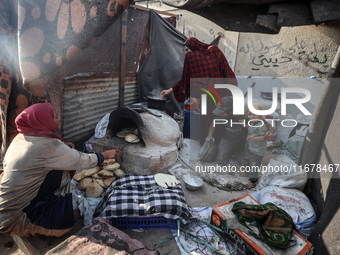 A Palestinian woman bakes bread at a makeshift camp for the internally displaced in Deir al-Balah in the central Gaza Strip on October 18, 2...