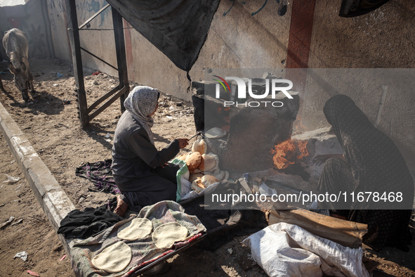 A Palestinian woman bakes bread at a makeshift camp for the internally displaced in Deir al-Balah in the central Gaza Strip on October 18, 2...