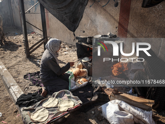 A Palestinian woman bakes bread at a makeshift camp for the internally displaced in Deir al-Balah in the central Gaza Strip on October 18, 2...